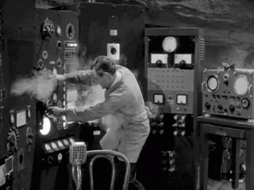 A Black And White Photo Of A Man Working On A Machine In A Room . GIF