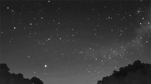 A Black And White Photo Of A Night Sky With A Shooting Star GIF