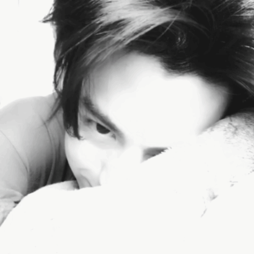 A Black And White Photo Of A Person Covering Their Face With A Pillow GIF