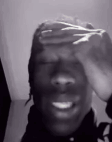 A Black And White Photo Of A Person Covering Their Face With Their Hands . GIF