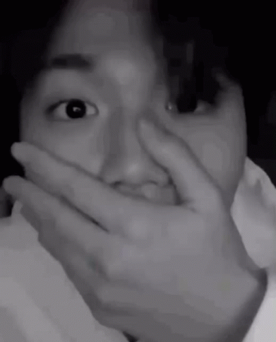 A Black And White Photo Of A Person Covering Their Mouth With Their Hand . GIF