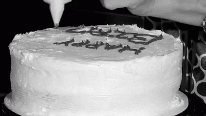 A Black And White Photo Of A Person Frosting A Cake With Icing . GIF