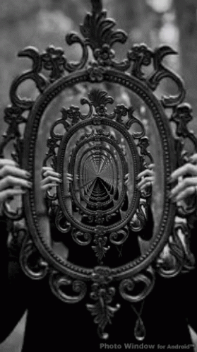 A Black And White Photo Of A Person Holding A Mirror With A Reflection Of A Tunnel In It GIF