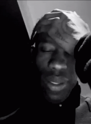 A Black And White Photo Of A Person Holding Their Head . GIF