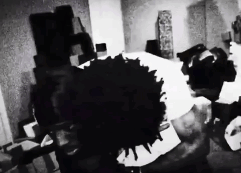 A Black And White Photo Of A Person Laying On A Bed With A Large Black Spot On The Floor . GIF