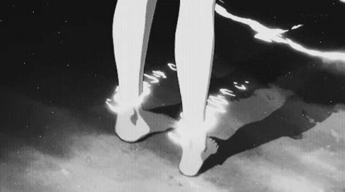 A Black And White Photo Of A Person 'S Feet Standing On A Beach . GIF