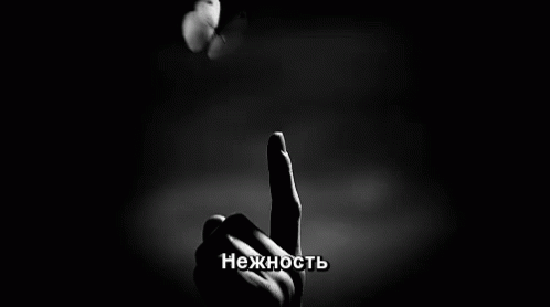 a black and white photo of a person 's finger with a butterfly on it