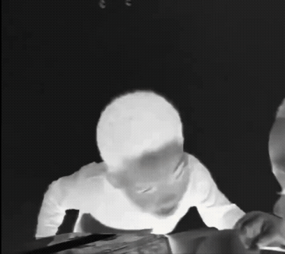 A Black And White Photo Of A Person Sitting At A Table With A Pencil In Their Hand . GIF