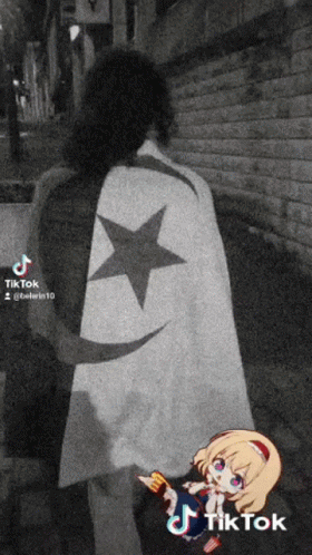 A Black And White Photo Of A Person Wearing A Cape With A Black Star On It GIF
