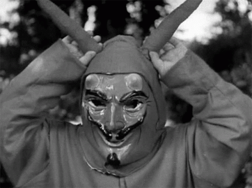 A Black And White Photo Of A Person Wearing A Devil Mask And A Hood . GIF