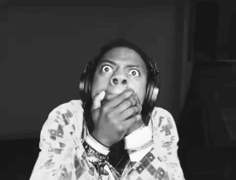 a black and white photo of a person wearing headphones and covering their mouth .
