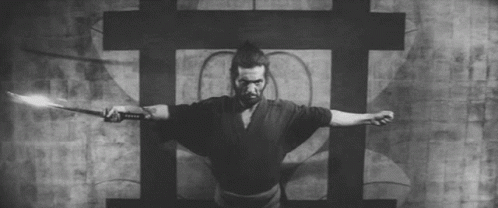 a black and white photo of a samurai holding a sword .