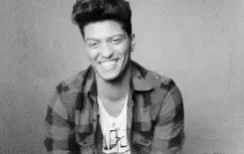 A Black And White Photo Of A Smiling Man In A Plaid Shirt . GIF
