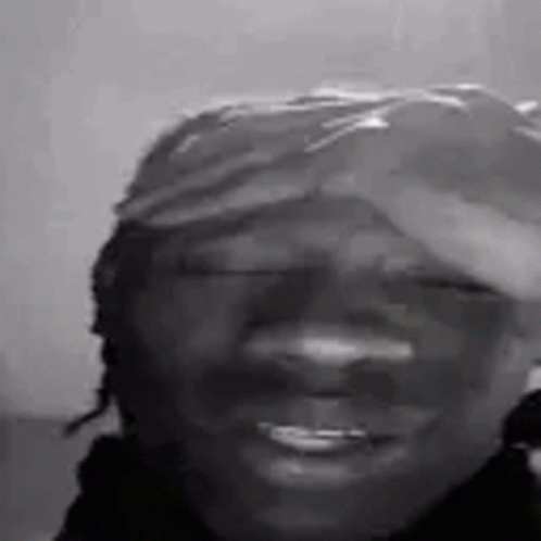 A Black And White Photo Of A Smiling Man Wearing A Hat . GIF