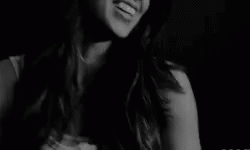 A Black And White Photo Of A Smiling Woman In A Dark Room . GIF