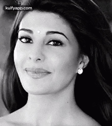 A Black And White Photo Of A Smiling Woman Wearing Earrings And A Bindi On Her Forehead . GIF