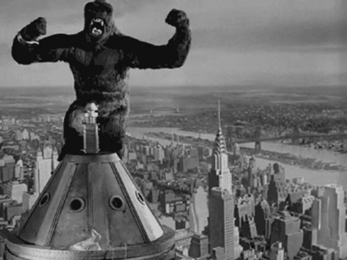 a black and white photo of a statue of a gorilla on top of a building