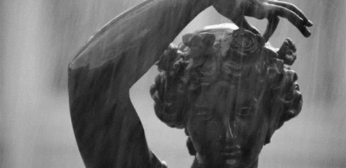 A Black And White Photo Of A Statue Of A Woman With Her Hand On Her Head GIF