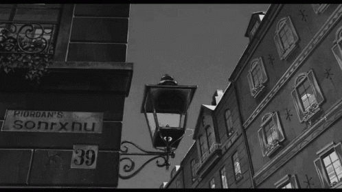A Black And White Photo Of A Street With A Sign That Says Riordan 'S Sonrxnu GIF