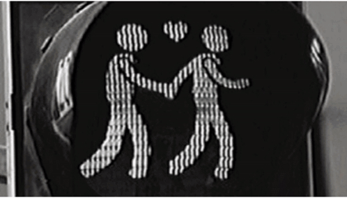 A Black And White Photo Of A Traffic Light With Two People Holding Hands GIF