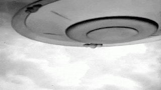 A Black And White Photo Of A Ufo Flying Through The Sky . GIF