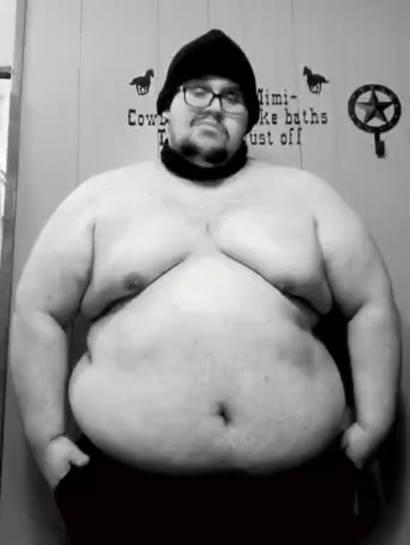A Black And White Photo Of A Very Fat Man With Glasses And A Beanie . GIF