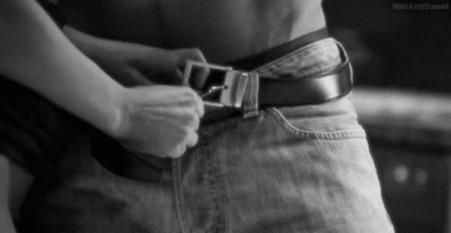 A Black And White Photo Of A Woman Adjusting A Belt On A Man 'S Waist . GIF