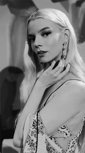 A Black And White Photo Of A Woman Adjusting Her Earrings GIF