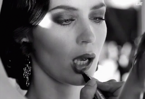 A Black And White Photo Of A Woman Applying Lipstick With The Letters Lje In The Corner GIF
