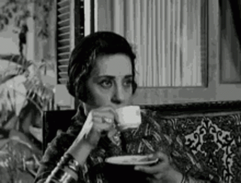 A Black And White Photo Of A Woman Drinking From A Cup . GIF