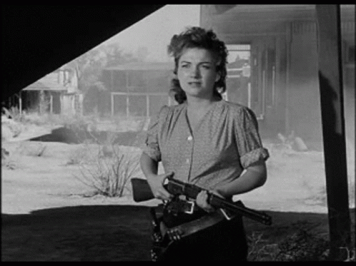 A Black And White Photo Of A Woman Holding A Gun In Her Hand . GIF
