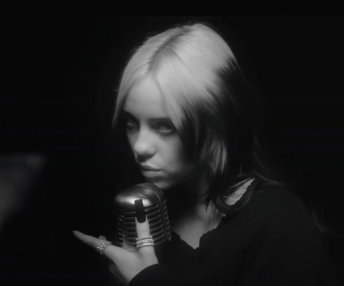 A Black And White Photo Of A Woman Holding A Microphone In Her Hand GIF