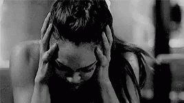 A Black And White Photo Of A Woman Holding Her Head In Pain . GIF