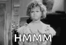 A Black And White Photo Of A Woman In A Dress With The Words `` Hmm '' Written On Her Face . GIF