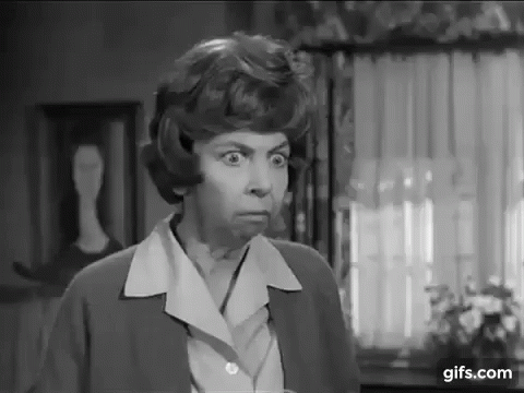 A Black And White Photo Of A Woman In A Living Room Making A Funny Face . GIF