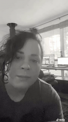 A Black And White Photo Of A Woman In A Living Room With A Laptop On A Desk . GIF
