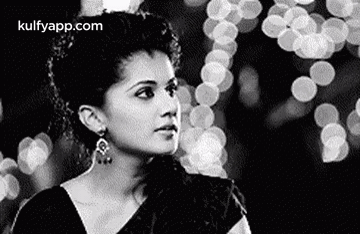 A Black And White Photo Of A Woman In A Saree Looking At The Camera . GIF