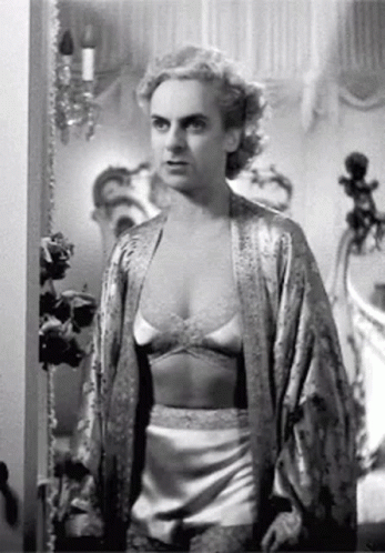 A Black And White Photo Of A Woman In Lingerie And A Robe Standing In A Room . GIF