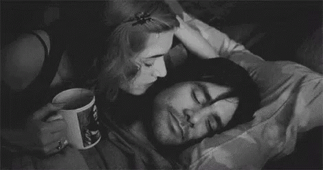 A Black And White Photo Of A Woman Kissing A Man On The Cheek . GIF