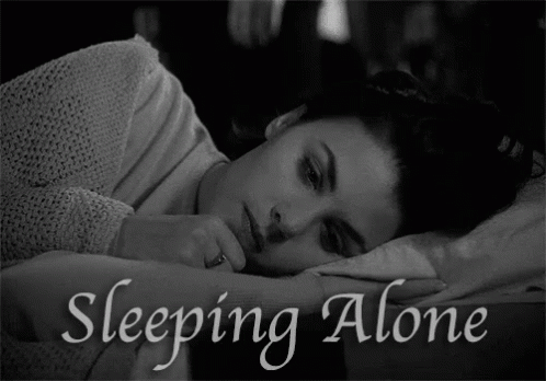 A Black And White Photo Of A Woman Laying In Bed With The Words Sleeping Alone Above Her GIF