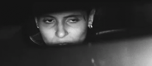 A Black And White Photo Of A Woman Looking At Herself In A Car Rear View Mirror . GIF