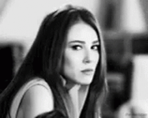 A Black And White Photo Of A Woman Looking At The Camera . GIF
