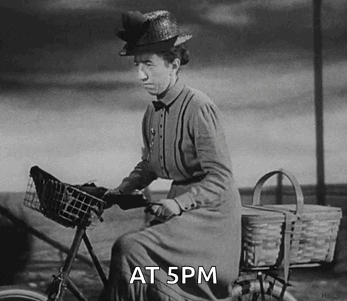 A Black And White Photo Of A Woman Riding A Bike With The Words At 5Pm Written Below Her GIF