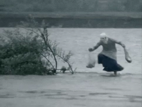 A Black And White Photo Of A Woman Running Through A Flooded Area . GIF