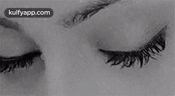 A Black And White Photo Of A Woman 'S Eyes Looking At The Camera . GIF