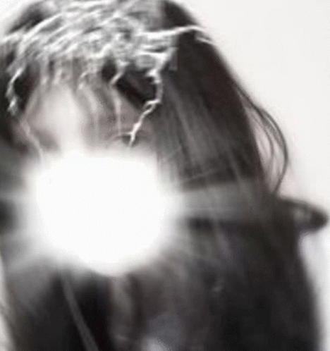 A Black And White Photo Of A Woman 'S Face With A White Light Behind Her . GIF