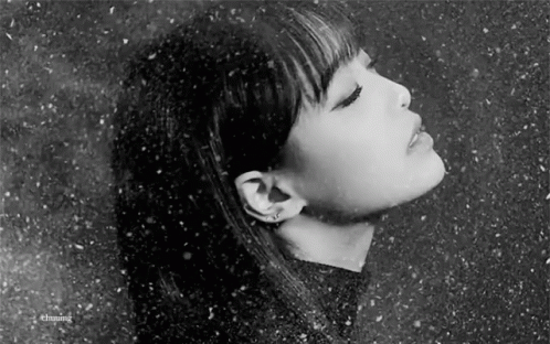 A Black And White Photo Of A Woman 'S Face With Her Eyes Closed In The Snow . GIF