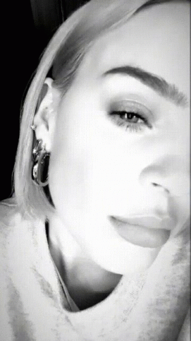 A Black And White Photo Of A Woman 'S Face With Hoop Earrings GIF