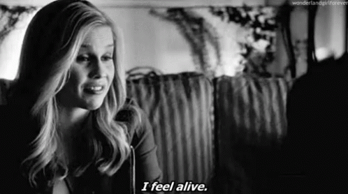 A Black And White Photo Of A Woman Saying `` I Feel Alive '' While Sitting On A Couch . GIF