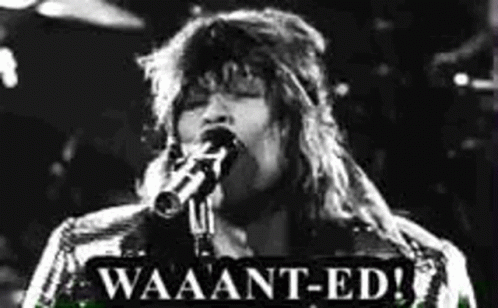 A Black And White Photo Of A Woman Singing Into A Microphone With A Sign That Says Waaant-Ed . GIF